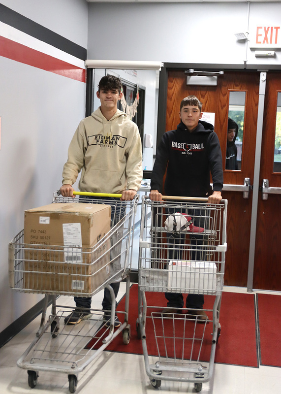 Sophomore Clay Told and senior Aiden Eidman walk into the building with shopping carts for no bag day. Photo by Linda Drake