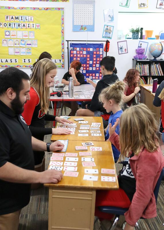 Music instructor David Magãna and freshman Reace Harshman play cards with students from Lisa Lauer's second grade class. Photo by Linda Drake